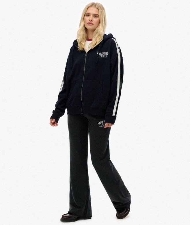 Person wearing a navy tracksuit with white stripes on a white background
