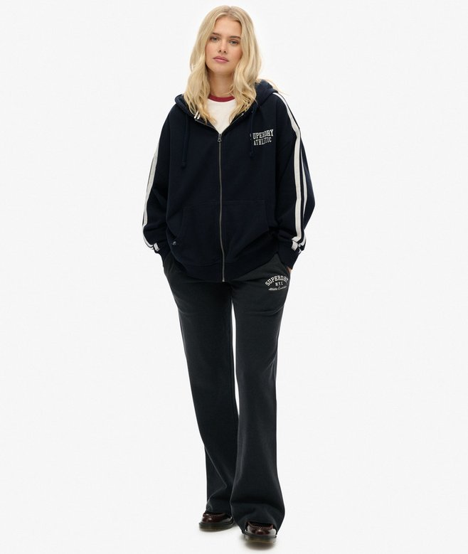 Person wearing a navy tracksuit with white stripes on a white background