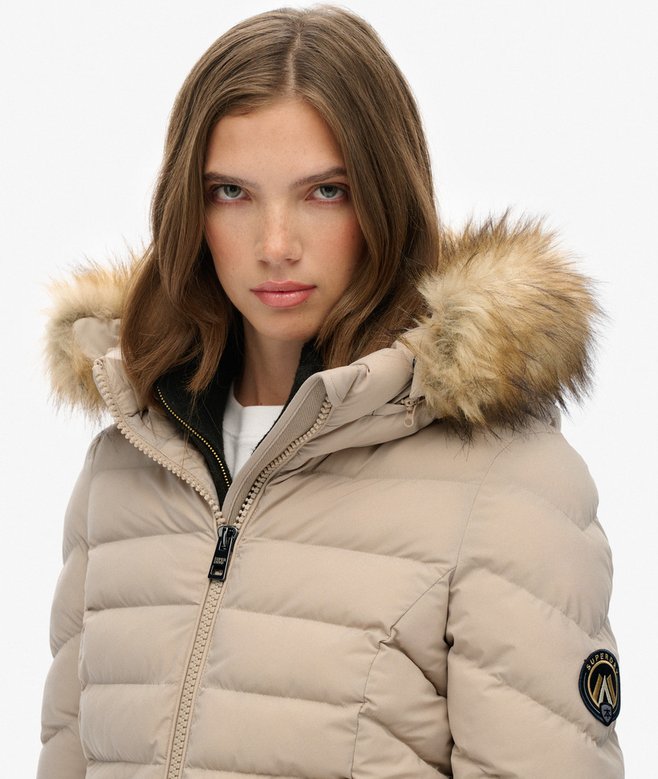 Beige puffer jacket with fur hood worn by a model on a white background