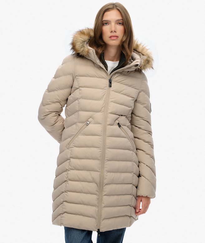 Woman wearing a beige puffer coat with fur hood on a white background