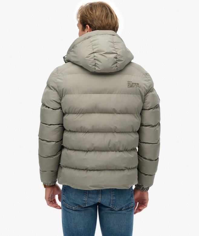 Person wearing a light green puffer jacket with a visible brand logo on a white background