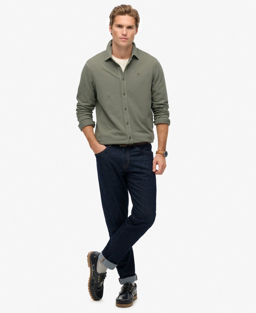 Man wearing a green shirt and dark pants on a white background