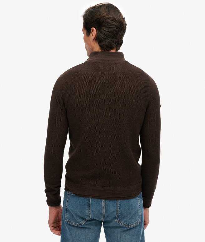 Man wearing a brown sweater and blue jeans on a white background