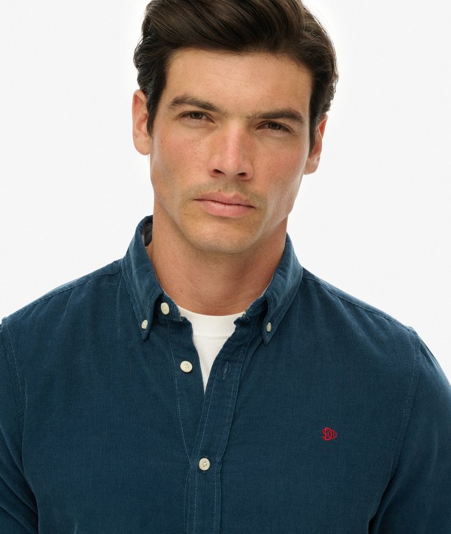 Man wearing a blue shirt with a red logo on a white background