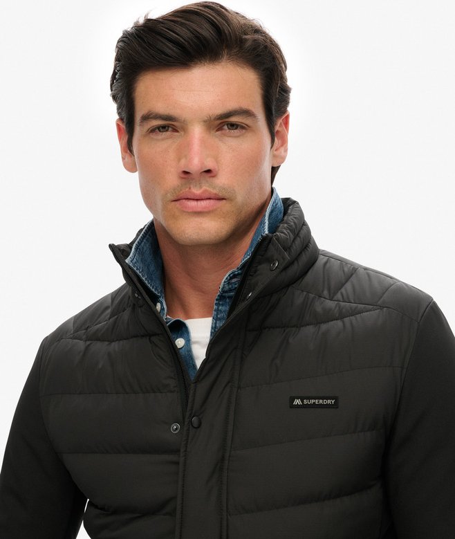 Man wearing a black puffer jacket with a visible brand logo on a white background