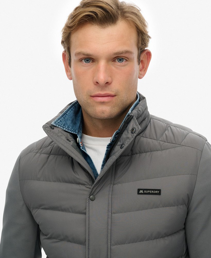 Man wearing a gray puffer jacket with a visible brand logo on a white background