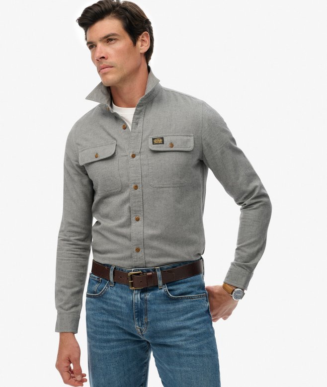 Man wearing a blue-gray button-up shirt and blue jeans on a white background