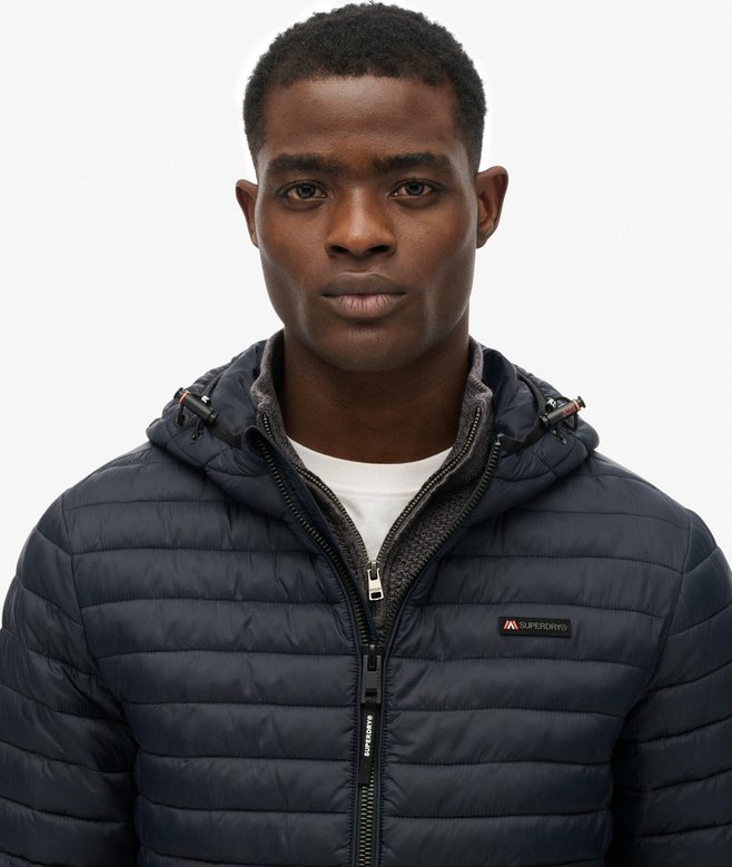 Person wearing a navy quilted jacket on a white background