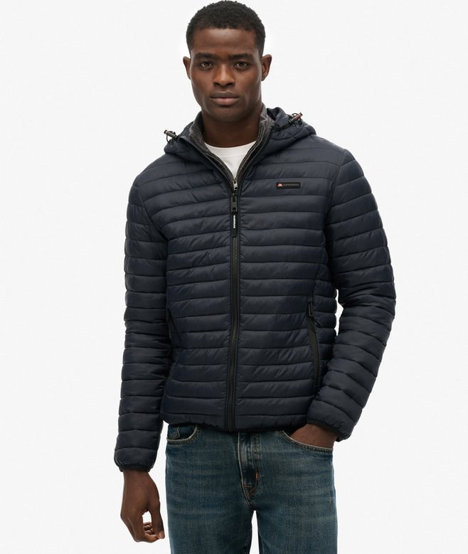 Person wearing a navy quilted jacket on a white background