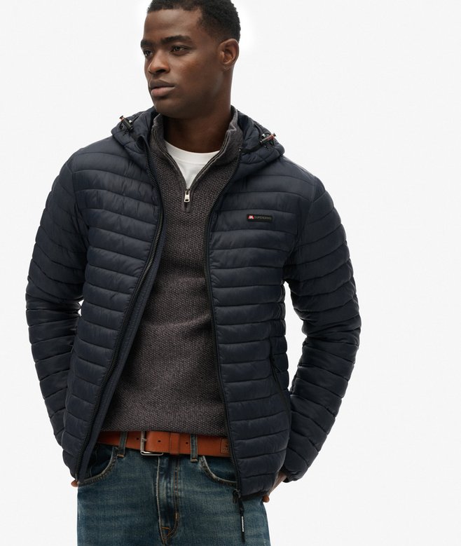 Person wearing a navy quilted jacket on a white background