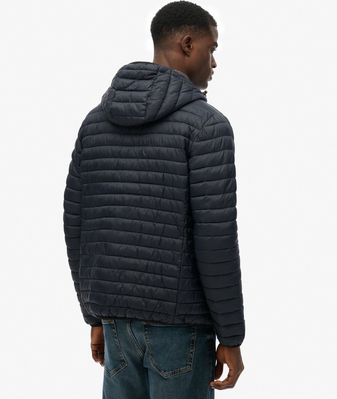 Person wearing a navy quilted jacket on a white background