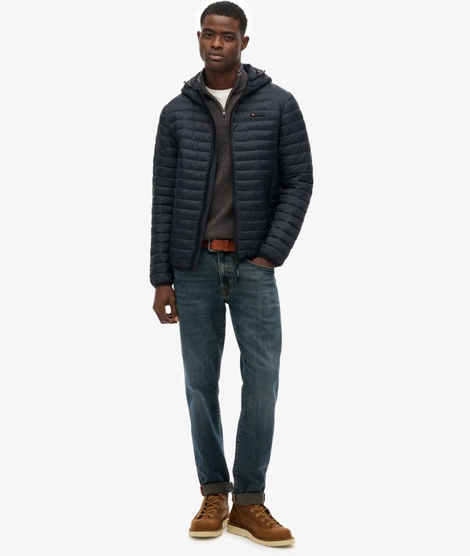 Person wearing a navy quilted jacket on a white background