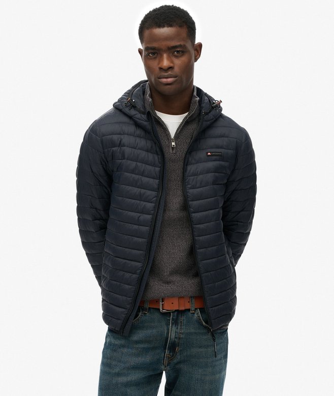 Person wearing a navy quilted jacket on a white background