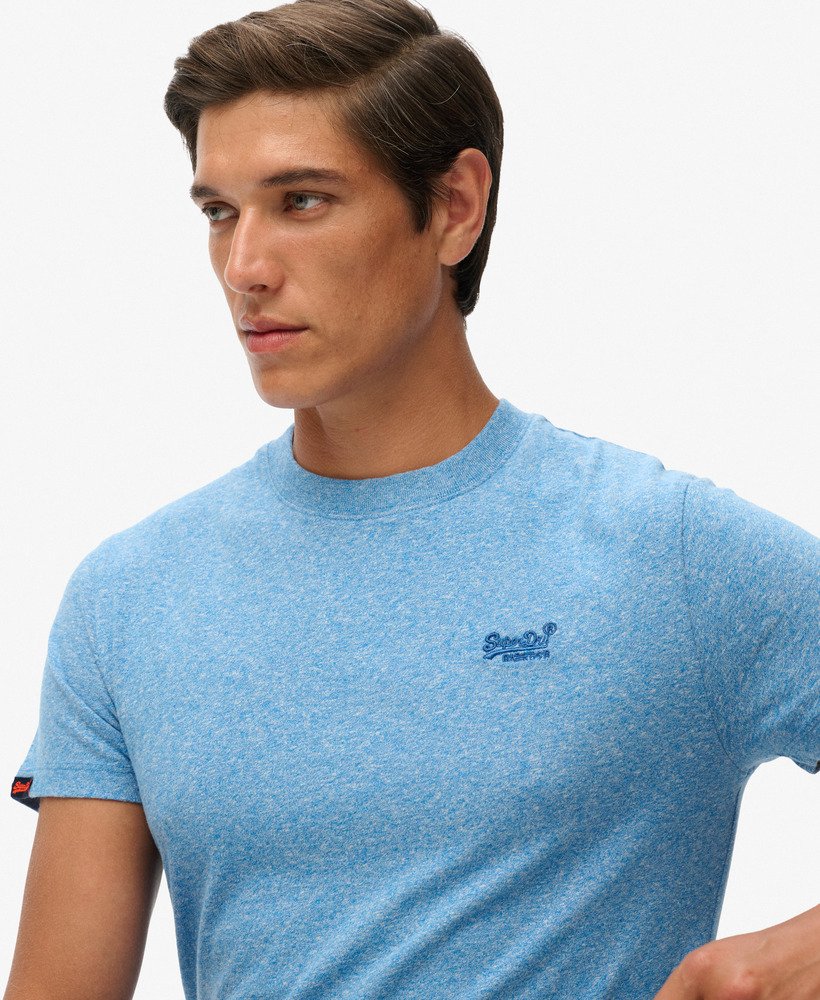 Man wearing a blue t-shirt with a brand logo on a white background