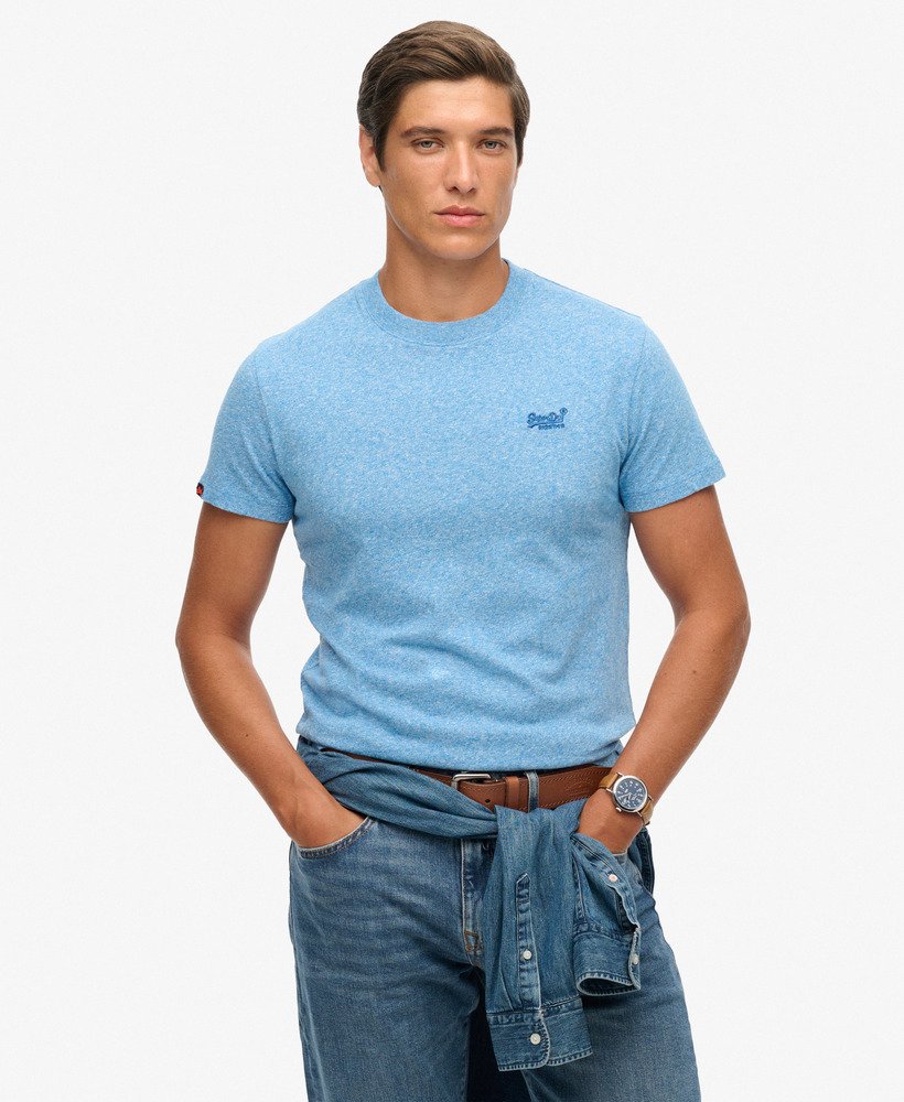 Man wearing a light blue t-shirt and jeans on a white background