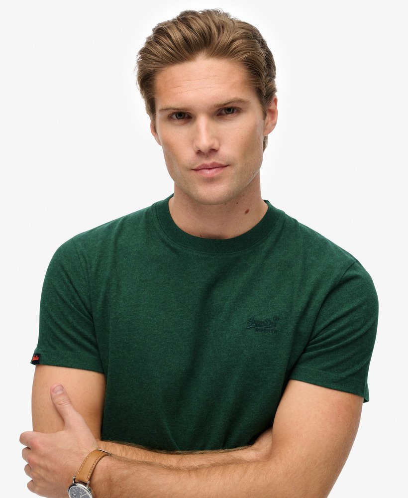 Man wearing a green t-shirt with a brand logo on a white background