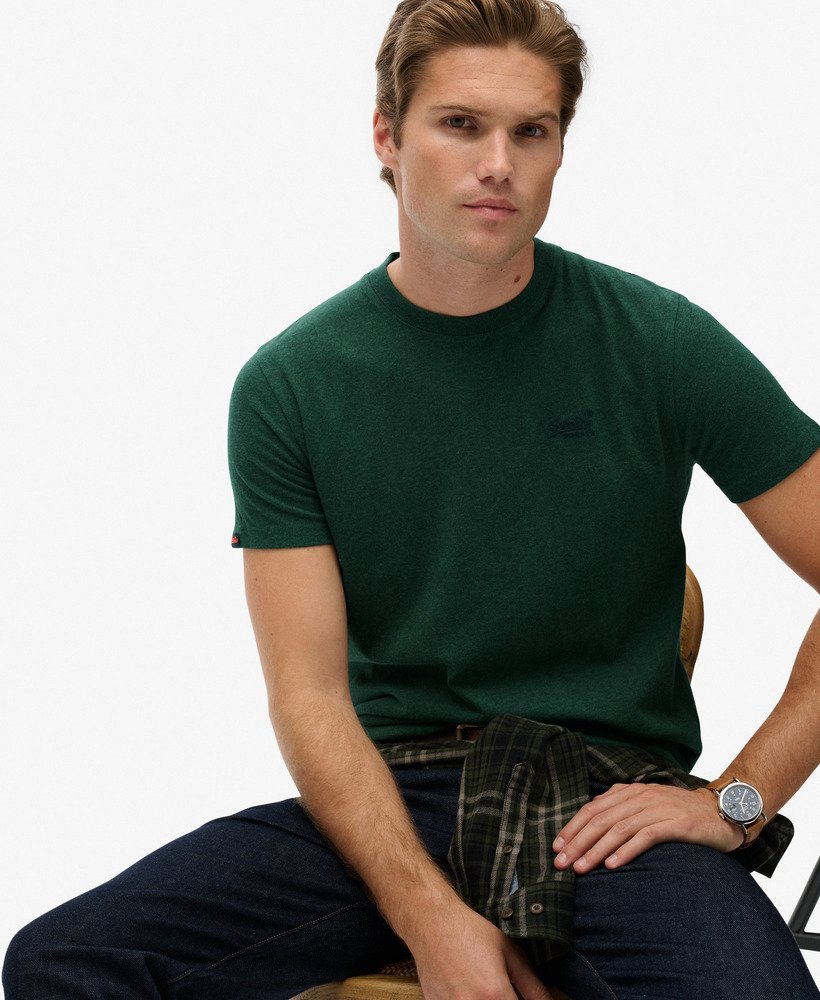 Man wearing a green t-shirt with a brand logo on a white background