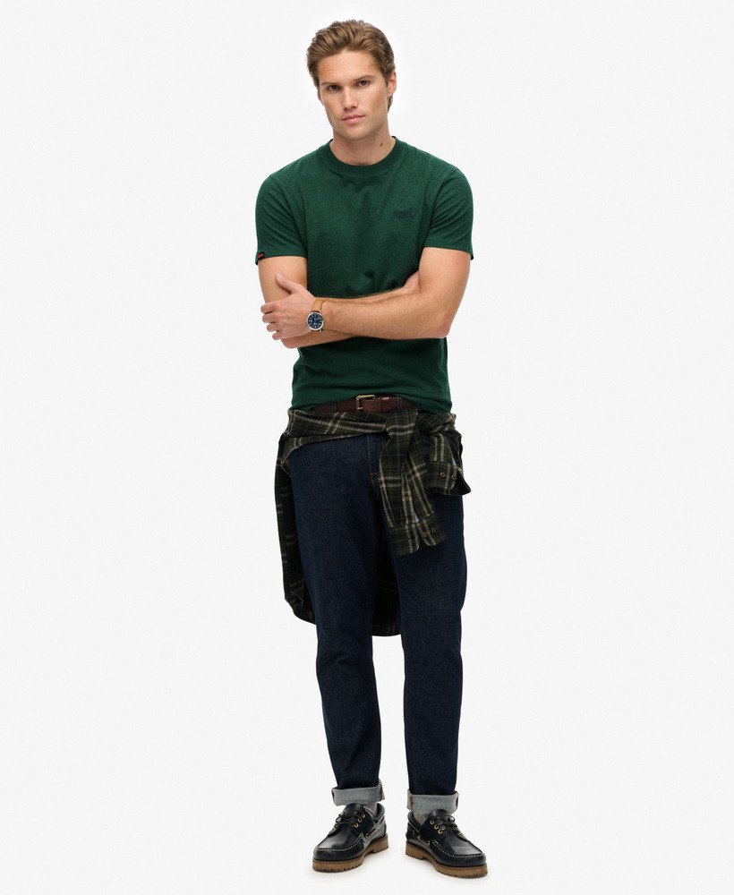 Man wearing a green t-shirt with a brand logo on a white background