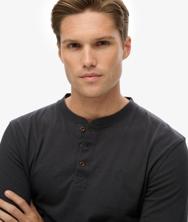 Man wearing a dark gray henley shirt against a plain background