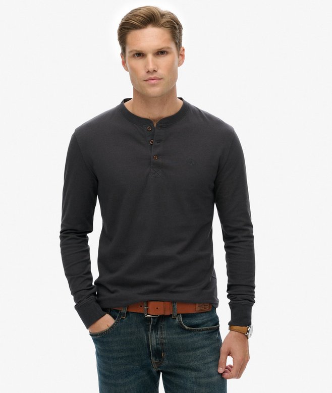 Man wearing a dark gray long-sleeve henley shirt and jeans on a white background
