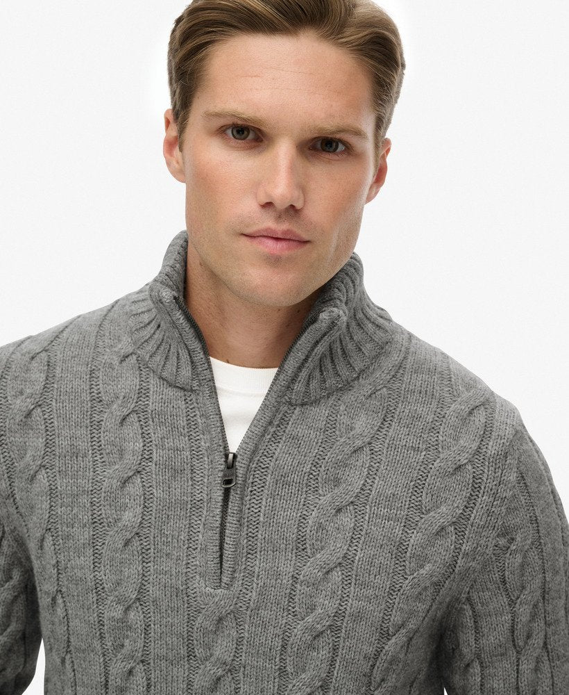 Man wearing a gray cable knit sweater with a white background