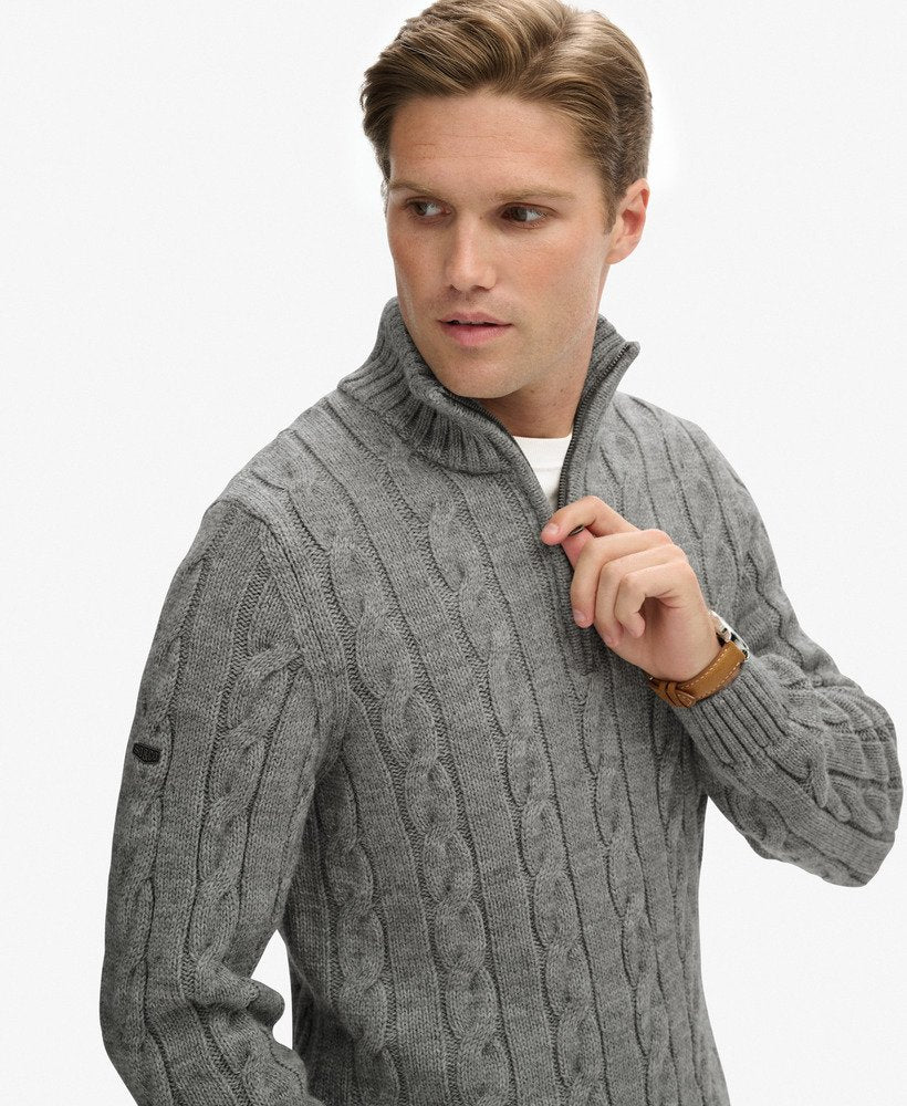 Man wearing a gray cable knit sweater on a white background