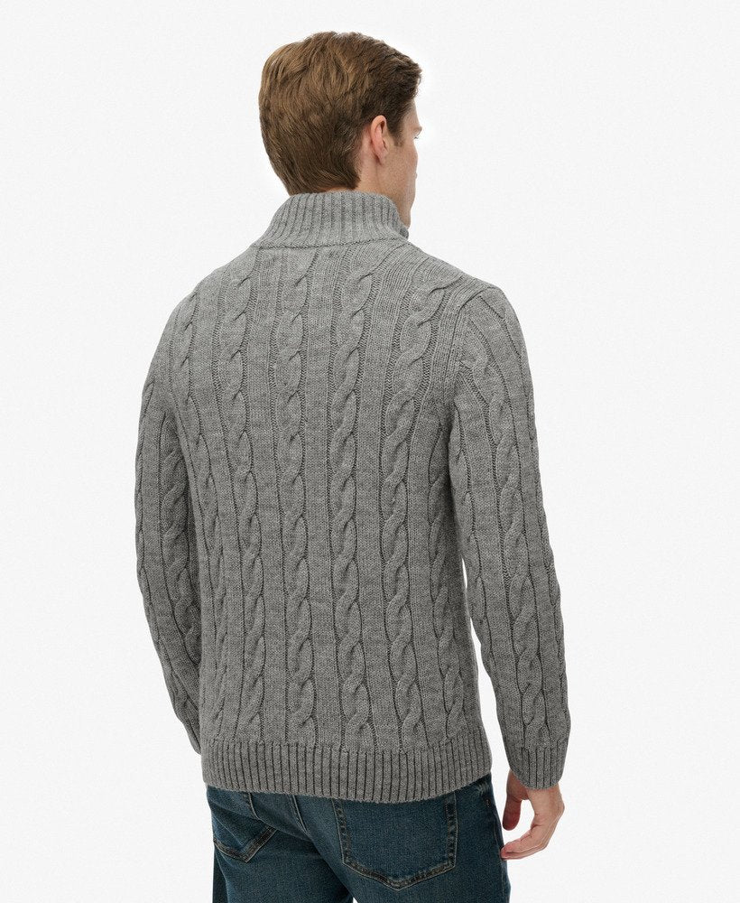 Man wearing a gray cable knit sweater on a white background