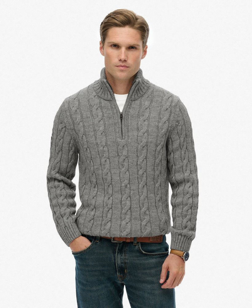 Man wearing a gray cable knit sweater on a white background