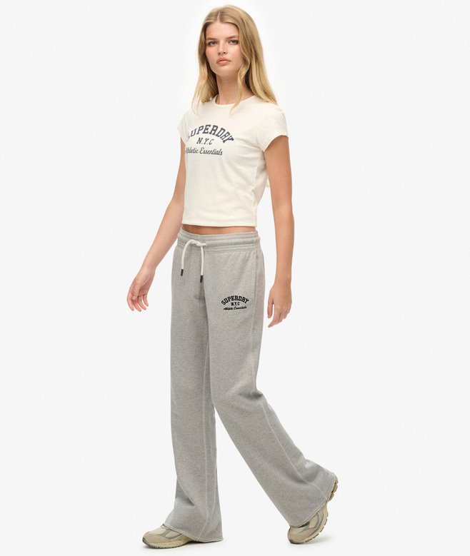 Woman wearing a white t-shirt and gray sweatpants with Superdry branding on a white background
