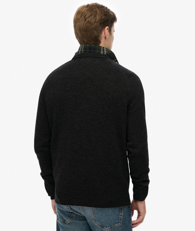 Man wearing a dark grey sweater with plaid collar on a white background