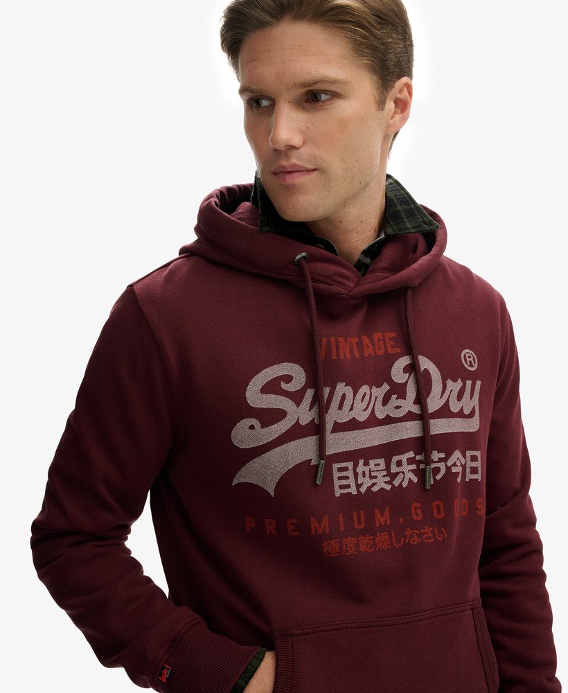 Man wearing a maroon hoodie with SuperDry logo on a white background