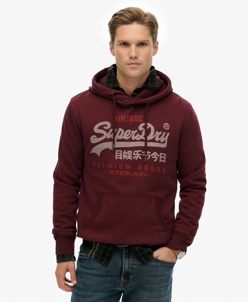 Man wearing a maroon hoodie with 'Superdry' logo on a white background