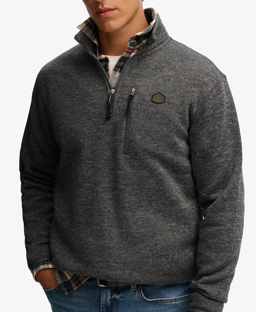 Man wearing a gray quarter-zip sweater with a brand logo on a white background