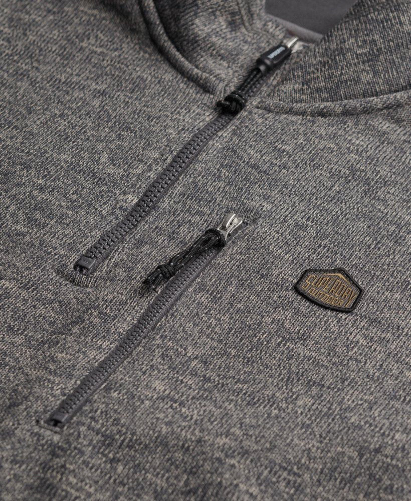 Close-up of a grey fleece with a zipper and brand logo.