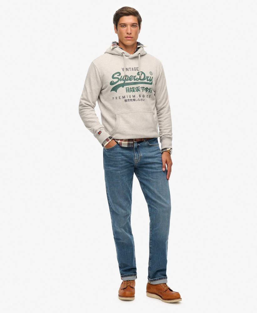 Man wearing a Superdry hoodie and blue jeans on a white background
