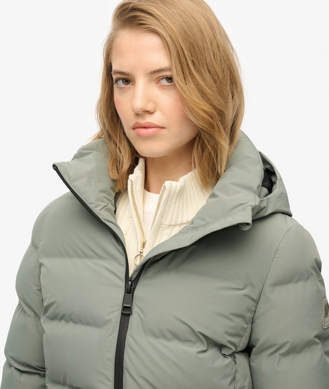 Woman wearing a green puffer jacket on a white background