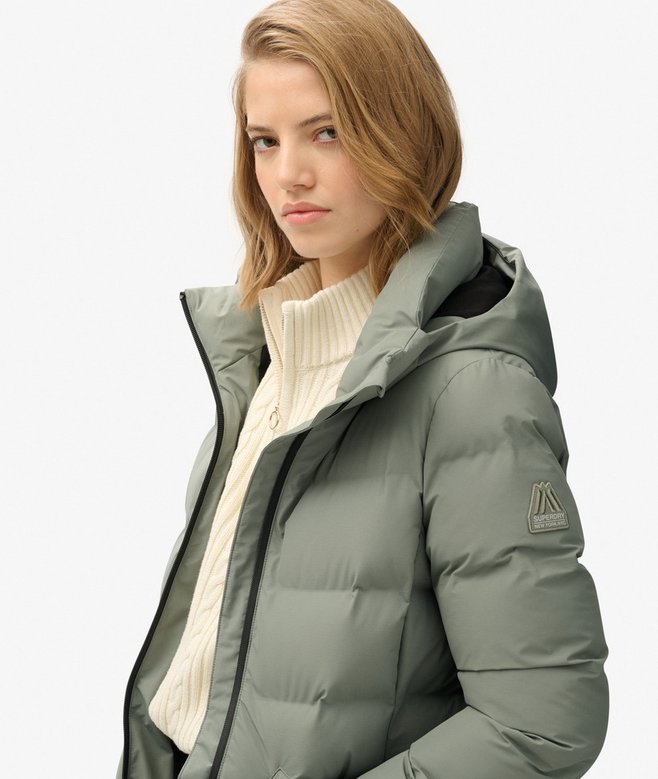 Woman wearing a green puffer jacket on a white background