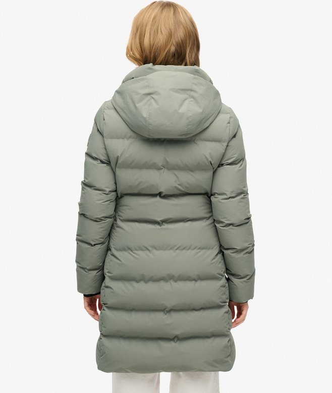 Person wearing a long green puffer coat on a white background