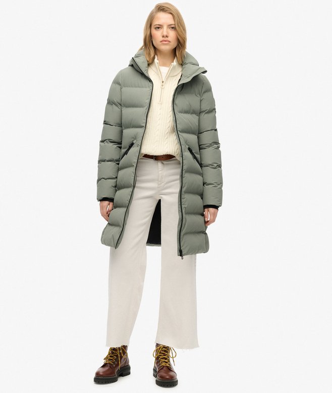 Person wearing a long green puffer coat on a white background