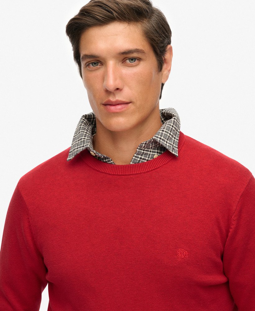 Man wearing a red sweater with a plaid collar against a white background