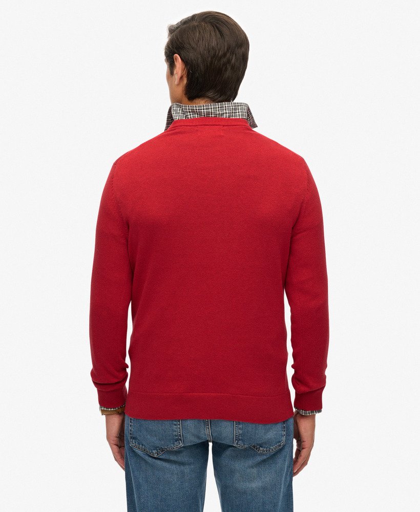 Person wearing a red sweater and blue jeans on a white background