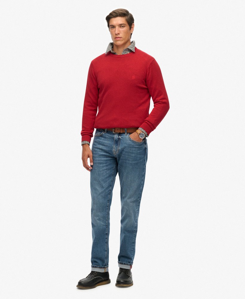 Man wearing a red sweater and blue jeans on a white background