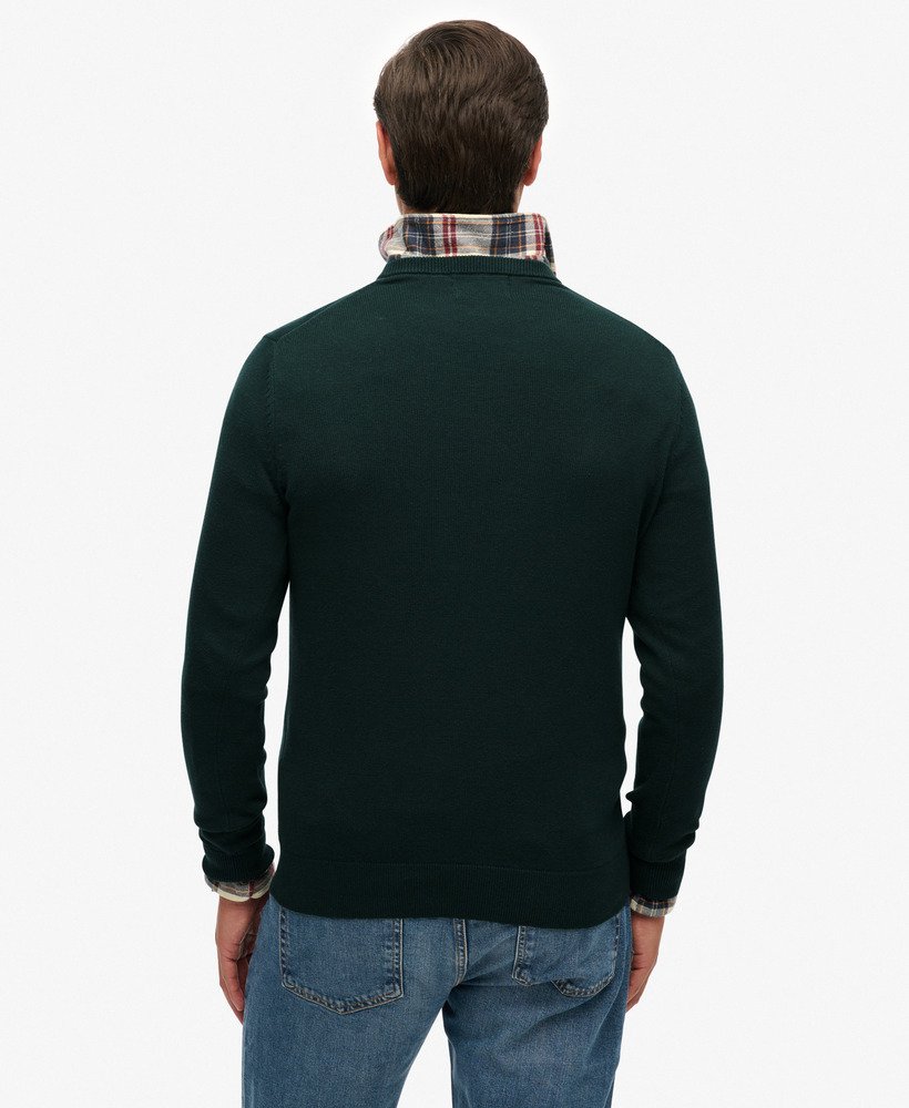 Man wearing a dark green sweater with a plaid collar on a white background