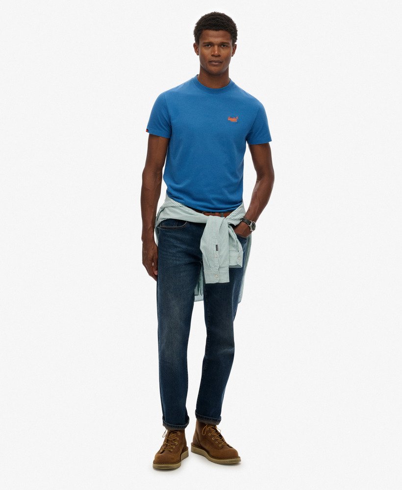 Man wearing a blue t-shirt, jeans, and brown boots on a white background