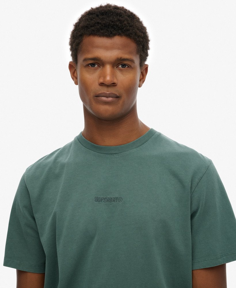 Man wearing a green t-shirt with a logo on a white background