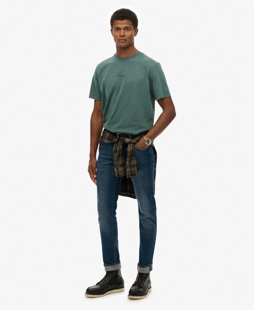 Man wearing a green t-shirt, blue jeans, and black boots on a white background