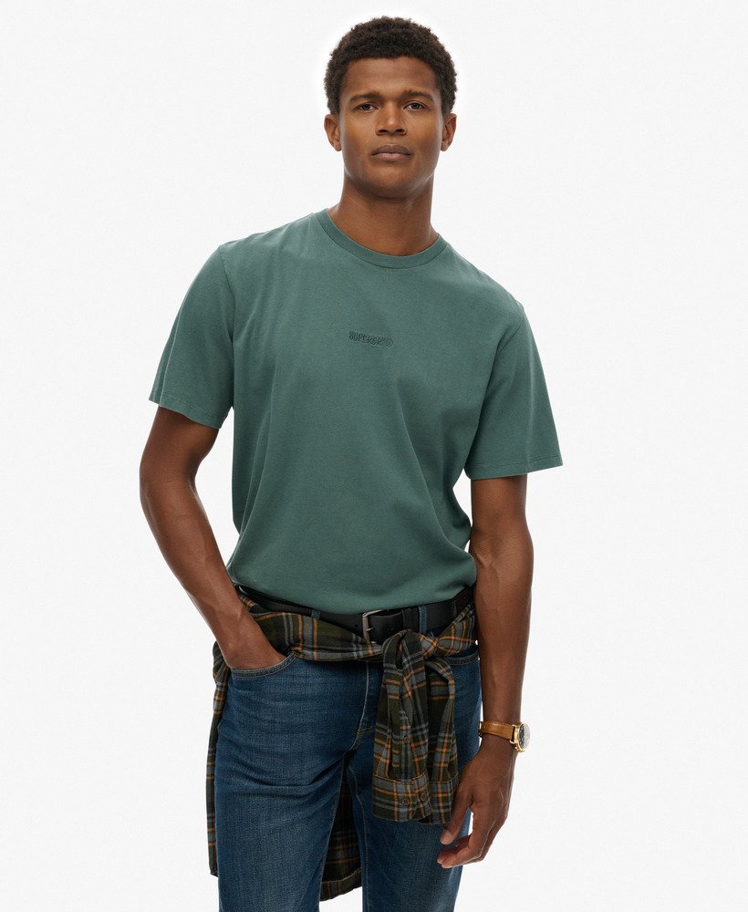 Man wearing a green t-shirt and blue jeans with a plaid apron on a white background