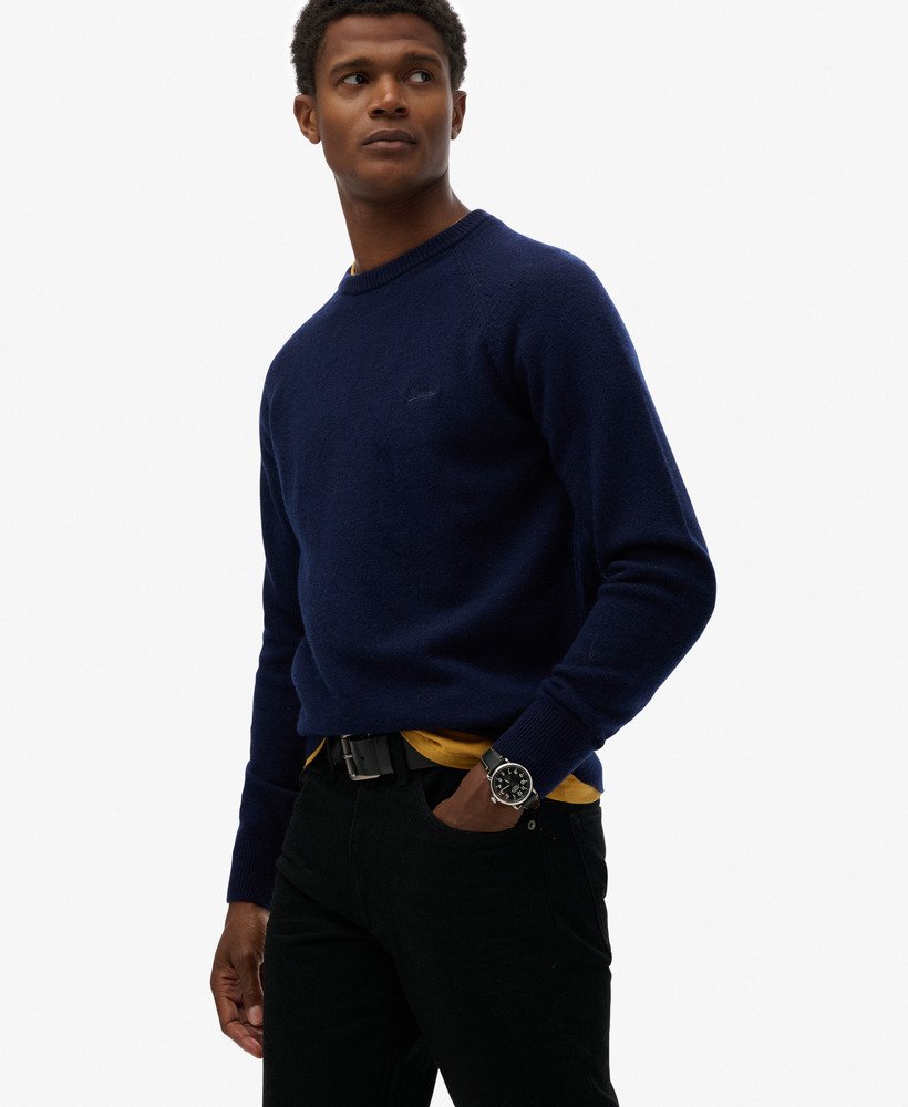 Man wearing a navy sweater with a visible brand logo on a white background