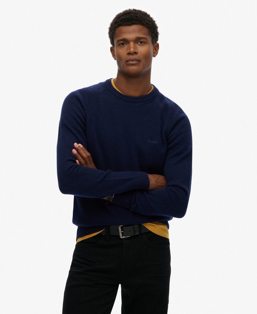 Man wearing a navy sweater with a logo on a white background