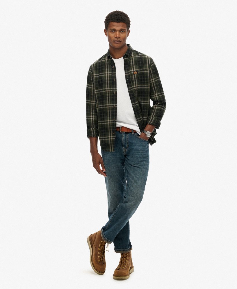 Man wearing a plaid shirt, white t-shirt, jeans, and brown boots on a white background